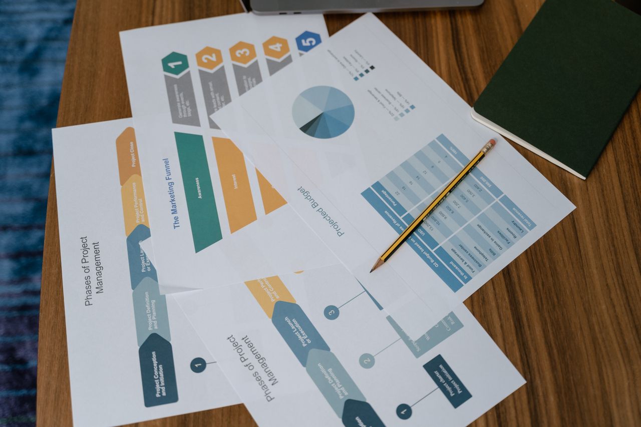 Vue plongeante sur des documents et des graphiques de gestion de projet posés sur un bureau, avec un crayon.